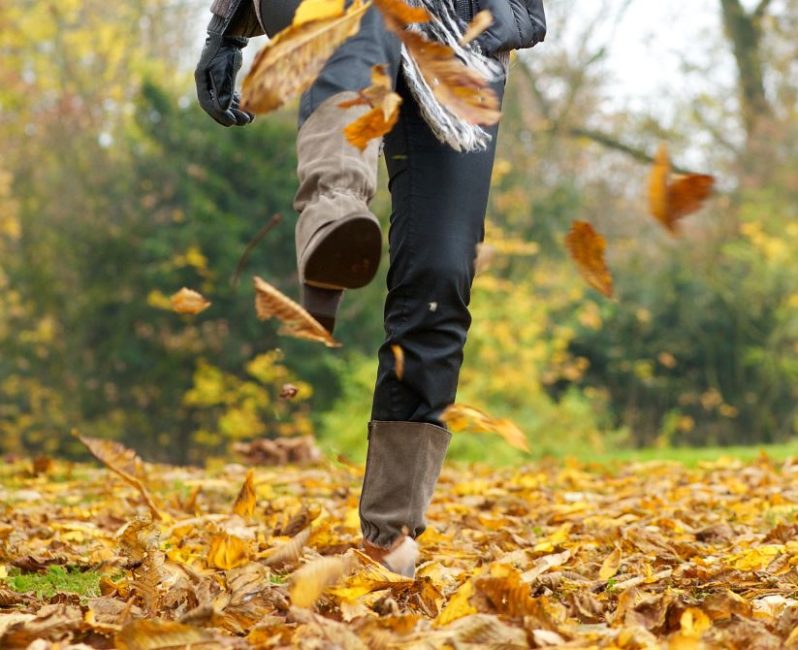Woman kicking up Autumn leaves in a pair of boots